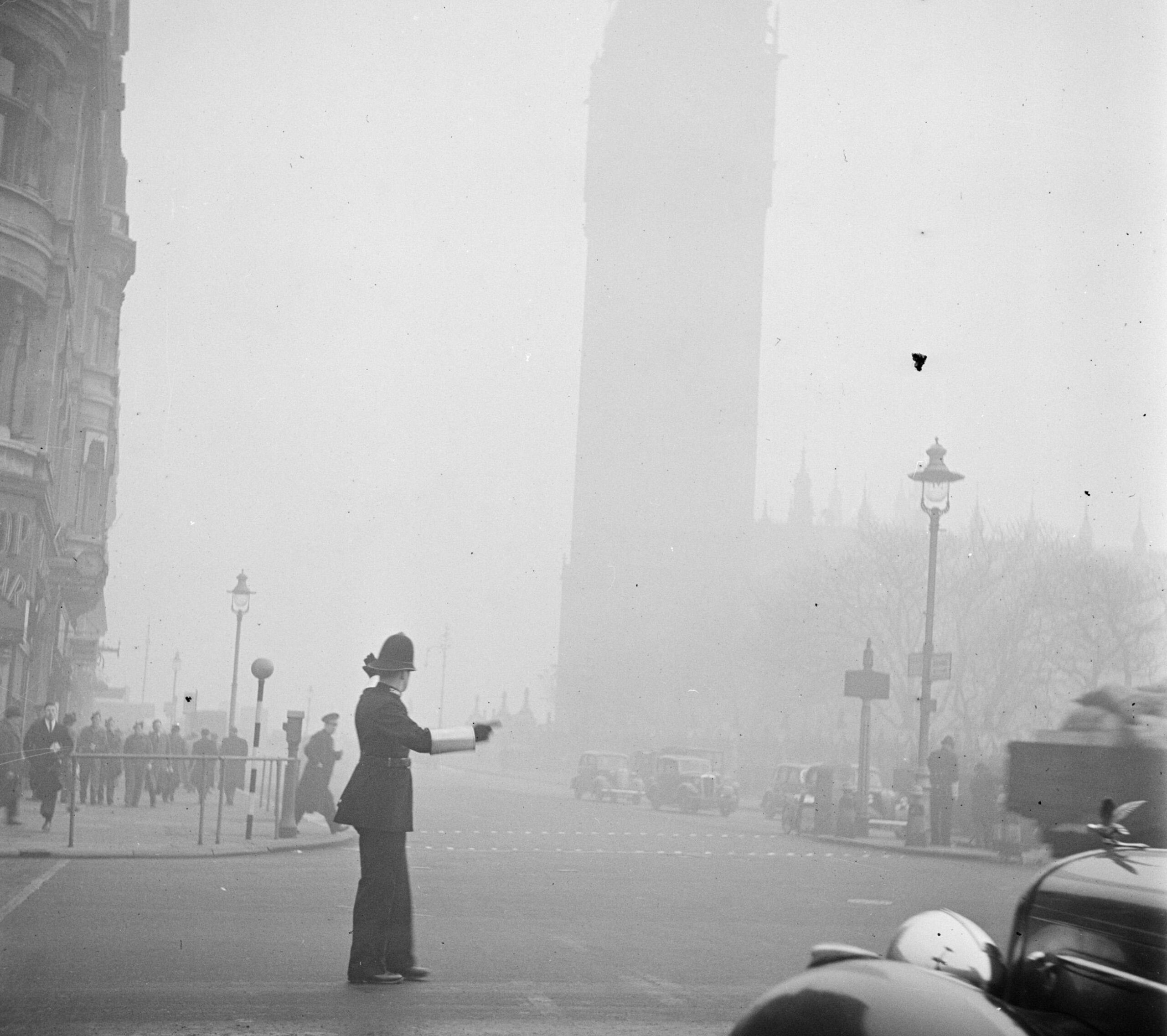 Een agent regelt het verkeer in de mist Op de achtergrond is Big Ben te zien Bestanddeelnr 254 1948 scaled 1